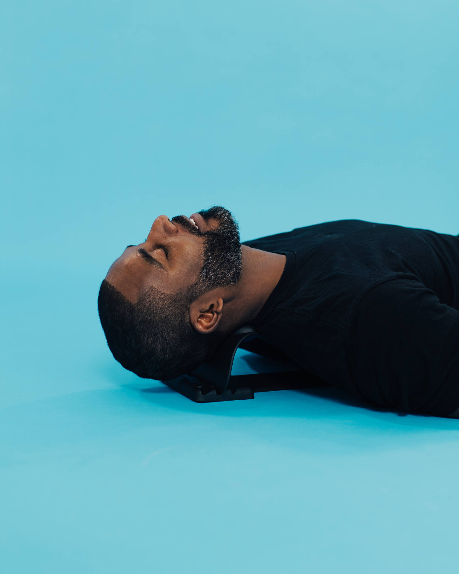 Man lying down using the iGel neck stretcher under the base of his skull