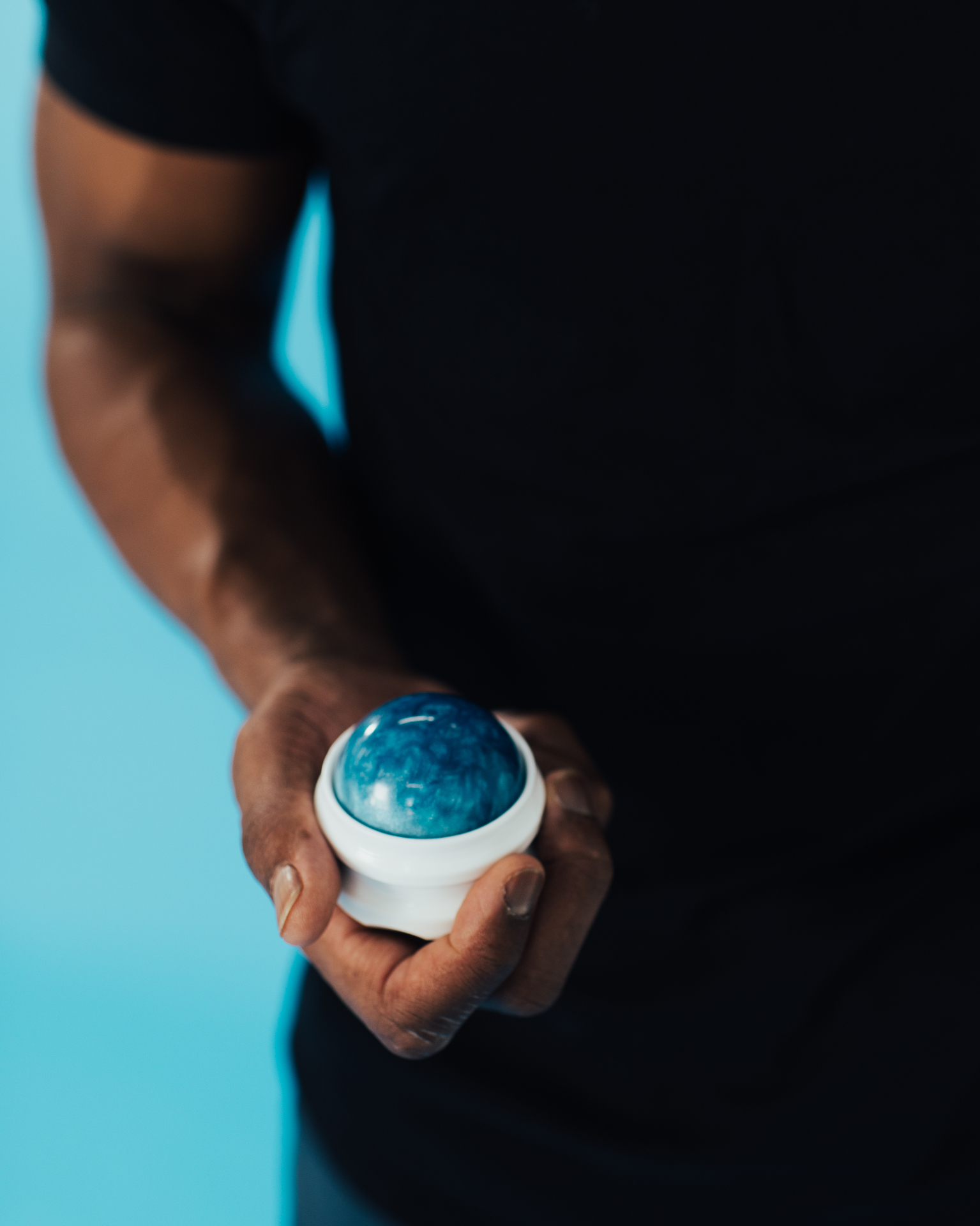 Hand holding the blue and white iGel rolling massage ball